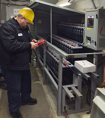 service tech testing stationary batteries with handheld battery analyzer